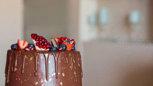 istock Appetizing chocolate cake decorated with strawberries, blueberries and a pomegranate on an orange background. 1277825568