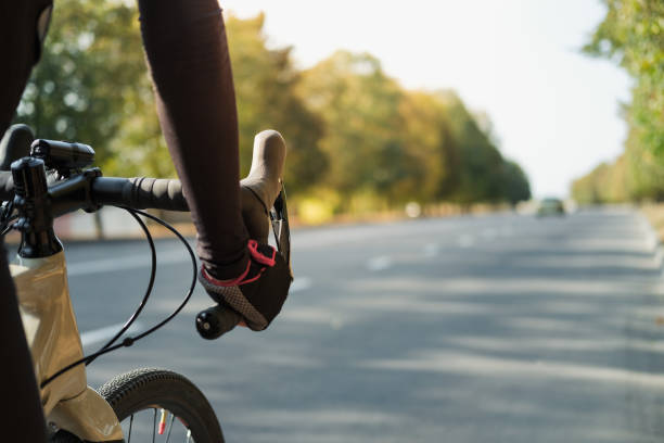 istock Hands of a cyclist resting on road bike handlebars, road view with copy space. 1277831733
