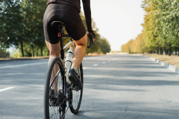 hombre en una bicicleta de grava en la carretera, vista trasera. - racing bicycle fotografías e imágenes de stock