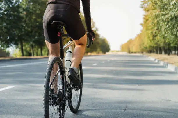 Photo of Man on a gravel bike on the road, back view.