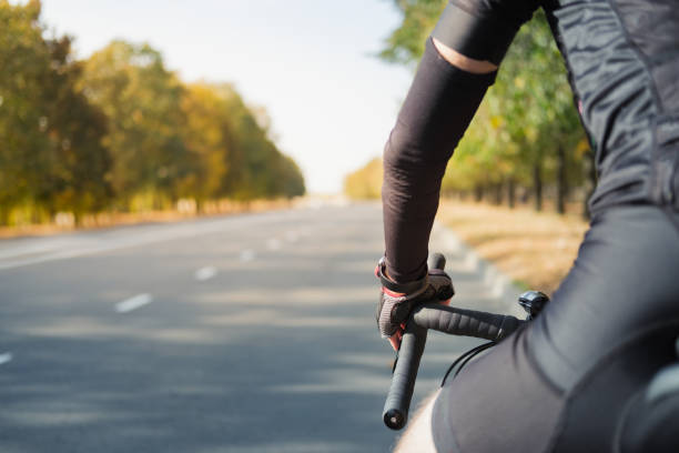 istock Hands of a cyclist resting on road bike handlebars, road view with copy space. 1277831794