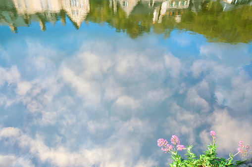 Reflection of buildings and cloudy sky in the Rance river at the medieval port of Dinan, Brittany, France.