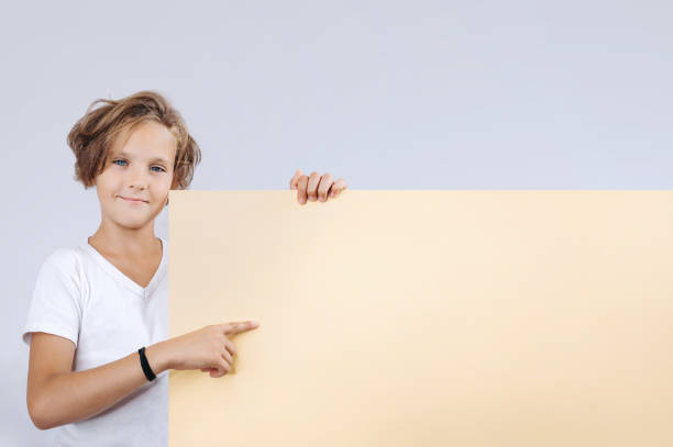 istock Cute young happy boy holding blank yellow board on white background 1277834087
