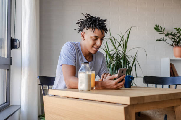 istock Young African American man eating breakfast and using smart phone 1277836295