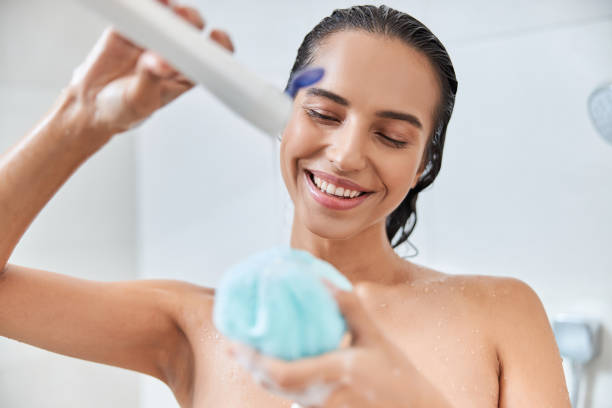 encantadora joven vertiendo gel de ducha en el baño loofah - shower gel fotografías e imágenes de stock