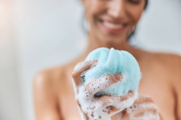 Charming young woman holding bath loofah sponge Close up of smiling lady with foamy exfoliating washcloth in her hand taking shower at home loofah photos stock pictures, royalty-free photos & images