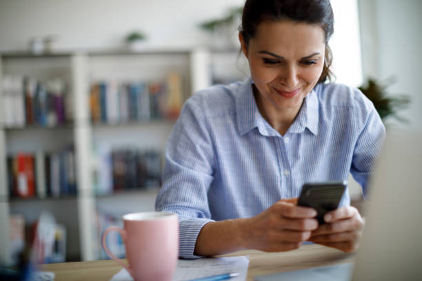 istock Smiling mature woman using mobile phone at home 1277837721