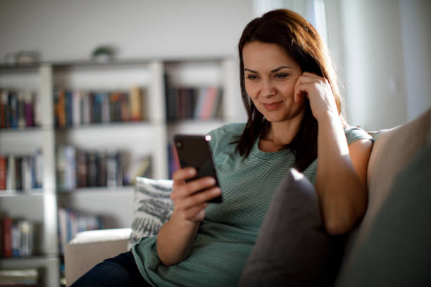 mulher madura sorridente usando celular em casa - woman cellphone - fotografias e filmes do acervo