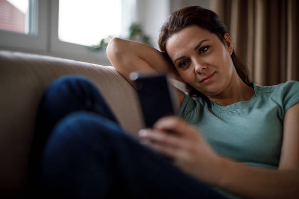 istock Smiling mature woman using mobile phone at home 1277838815