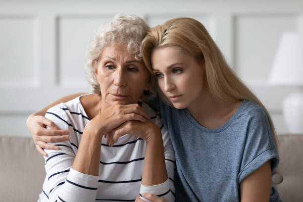 грустная взрослая дочь, сидящая на диване, обнимает отчаянную пожилую мать - adult thinking love caucasian стоковые фото и изображения