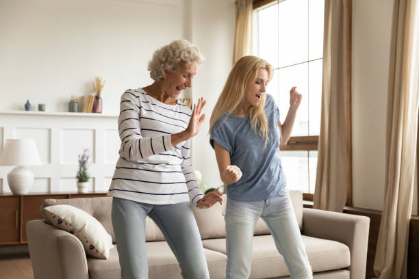 aged granny and grown granddaughter dancing at home celebrating housewarming - parent mother music listening imagens e fotografias de stock