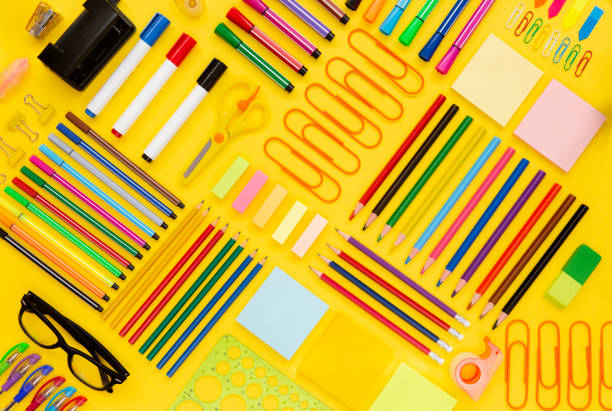 Office and school supplies arranged on yellow background