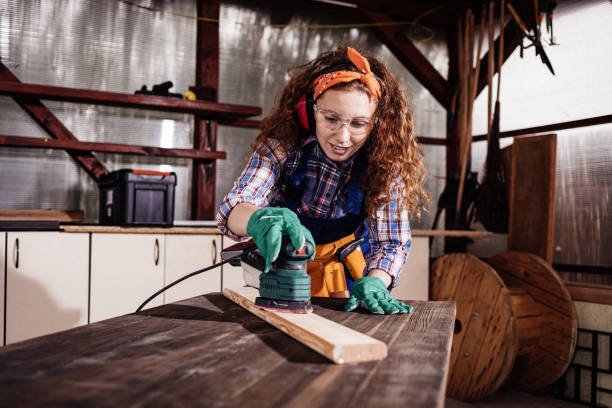 istock Young female carpenter grinding plank. 1277843279