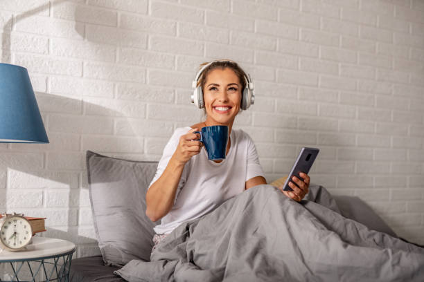 istock Young woman waking up and using smart phone in bed 1277850873