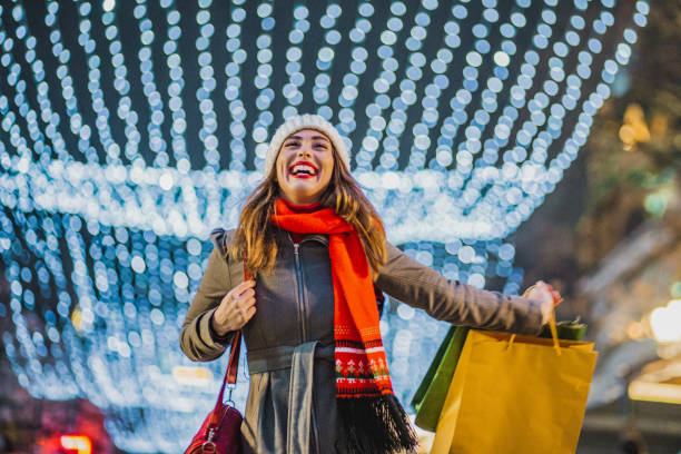 Young woman in a Christmas shopping Young woman walking with Christmas presents outdoors and laughing christmas excitement stock pictures, royalty-free photos & images