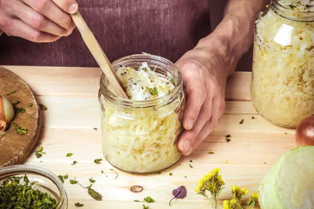 Cooking sauerkraut. Close-up of cropped hands and cabbage in a jar.