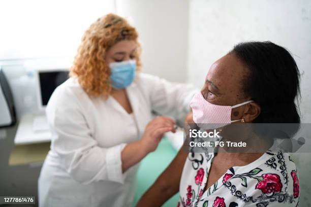 Nurse Applying Vaccine On Patients Arm Using Face Mask Stock Photo - Download Image Now