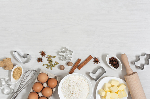 Ingredients for baking Christmas gingerbread cookies top view on white wooden background. Food bakery background.