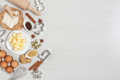 Ingredients for baking Christmas gingerbread cookies top view on white wooden background. Food bakery background.
