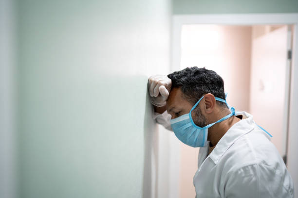 обеспокоенный врач в больнице - doctor tired protective workwear sadness стоковые фото и изображения