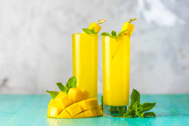 Refreshing summer cocktails made of mango, cold drink or a drink with ice on a blue gray background. Fresh summer ice cold mango cocktail or juice with mint and mango fruit stock photo