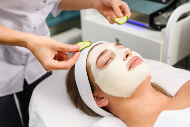 istock Cosmetologist put cucumber slices on client eyes 1277864477