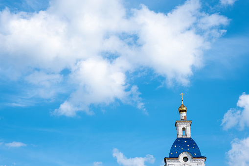 Bell tower with a golden dome and a cross of the Nikolo-Solbinsky nunnery against the background of the blue sky, Russia.
