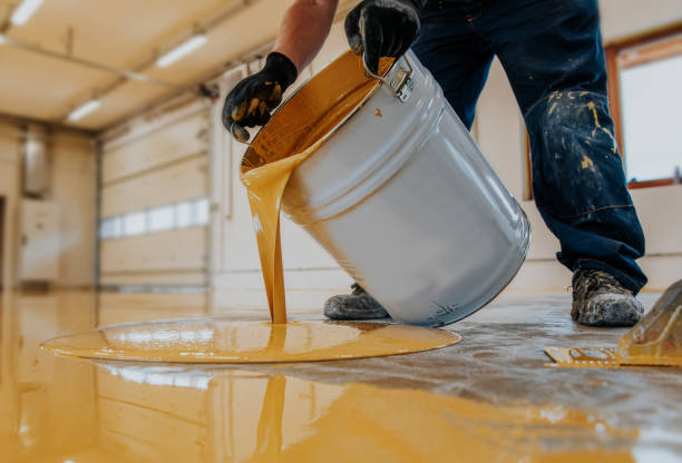 travailleur appliquant un seau jaune de résine époxy sur le plancher pour le manteau final. - industrial modern photos et images de collection