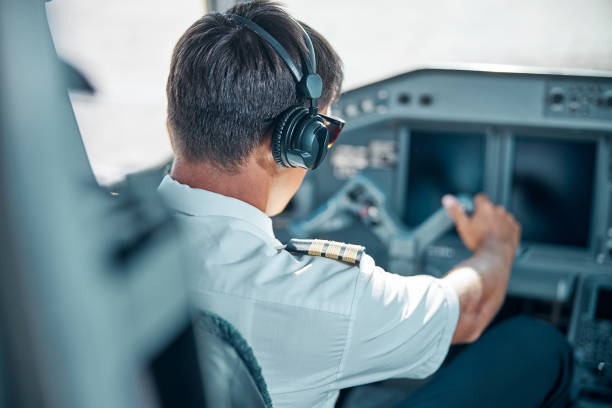 Young pilot taking off modern passenger plane Male professional in uniform and headphones is holding rudder at control while driving jet at work throttle stock pictures, royalty-free photos & images
