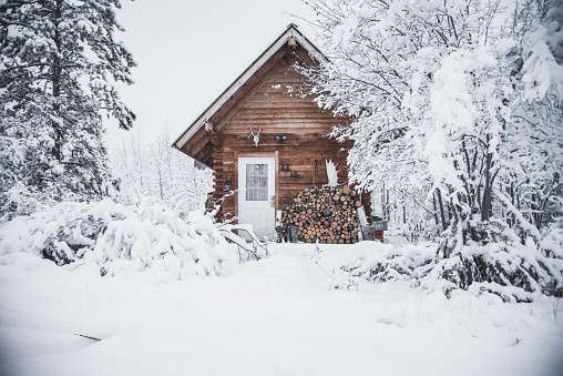 A cozy log cabin in the forest at winter time with lots of snow around