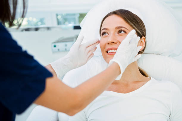Cosmetologist preparing patient for facial treatments Cosmetologist preparing to doing cosmetic facial treatments for the young woman dermatology stock pictures, royalty-free photos & images