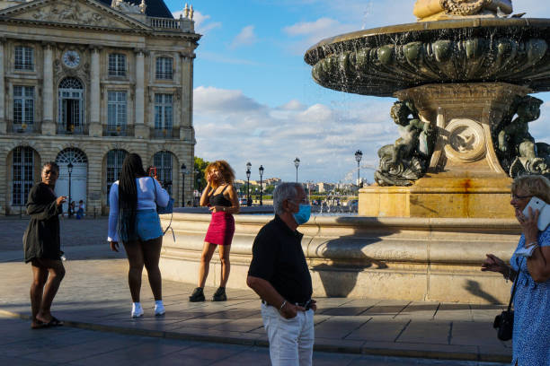 Bordeaux - 08/27/2020: tourists taking pictures and phoning near fountain in Place de la Bourse