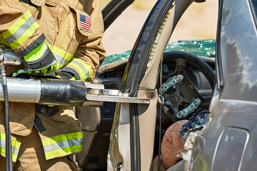 Paramedic Training class students learning rescue techniques using the Jaws of Life on a wrecked car with a dummy inside