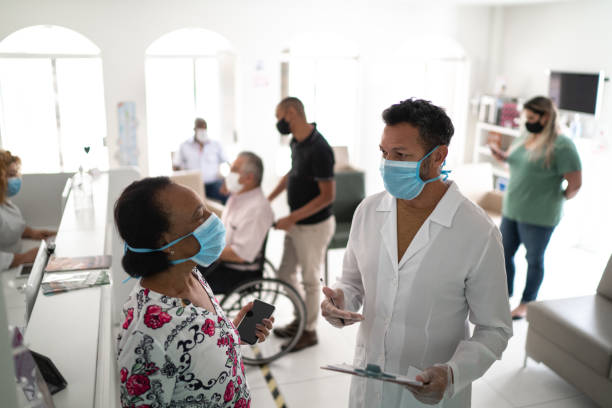 Patient arriving at medical clinic and being called by the doctor using face mask Patient arriving at medical clinic and being called by the doctor using face mask medical office lobby stock pictures, royalty-free photos & images