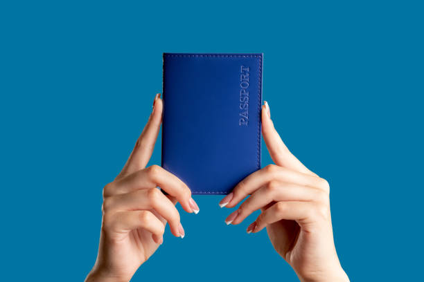passport service visa center hands national id Passport service. Visa center. Female hands holding national id book in blue cover isolated on bright copy space background. Legal document. Global immigration. blue us passport cover stock pictures, royalty-free photos & images