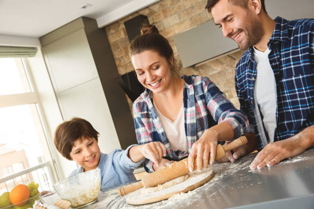 istock Family at home standing at table in kitchen rolling dough with pin together joyful 1277912323