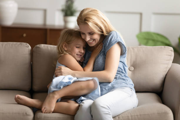 istock Little daughter and young mommy hugging on couch 1277914090
