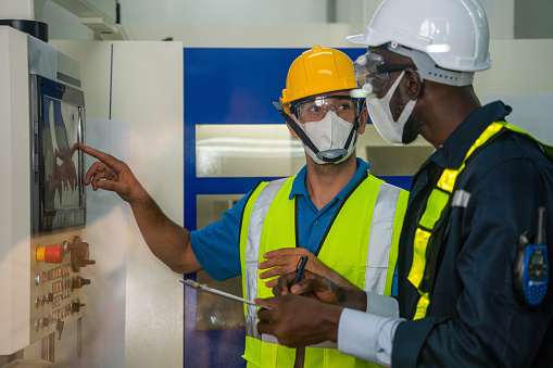 industrail background of factory workers wearing face mask to protect coronavirus covid-19 with safety vest and helmet having working detail brief from factory foreman in control room