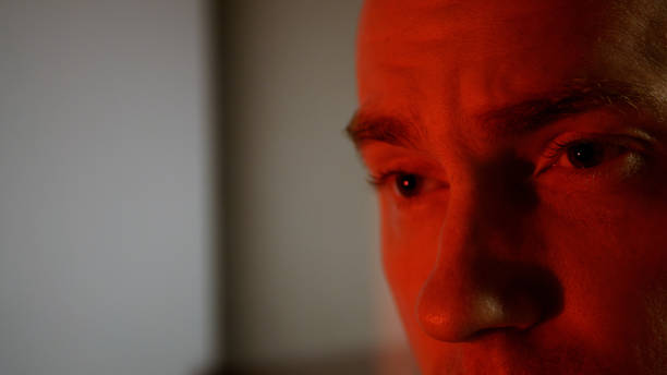 istock A young man with a serious look. Frowning man in red tones evil smile 1277920428