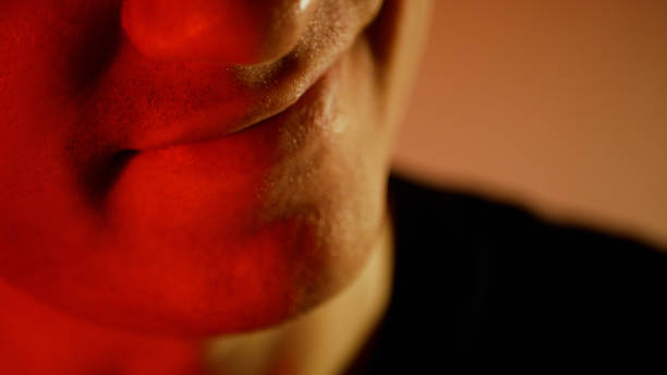 istock A young man with a serious look. Frowning man in red tones evil smile 1277920448