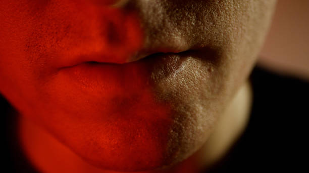 istock A young man with a serious look. Frowning man in red tones evil smile 1277920450