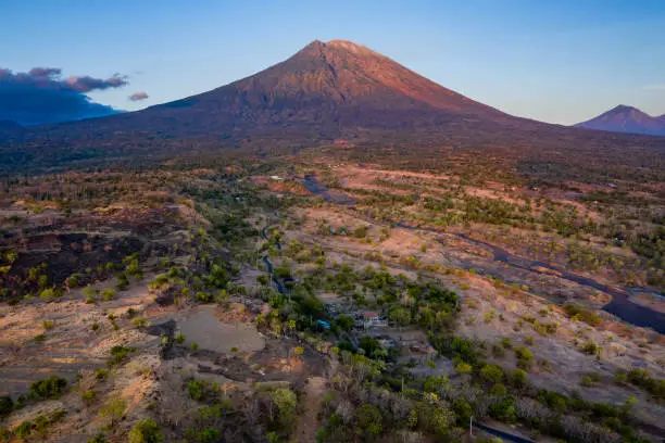 Early morning landscape view at sunrise and taken by drone of the volcano Mount Agung in Bali in Indonesia and slowly awaking from the night.
