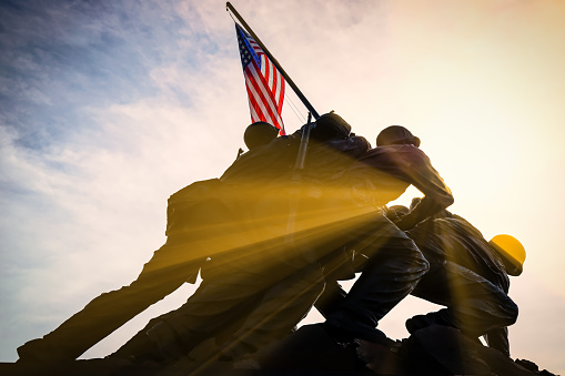 Arlington, Virginia / USA - September 7, 2018: The rising sun pokes through the US Marine Corps War Memorial designed by sculptor Felix de Weldon and architect Horace W. Peaslee which was unveiled on November 10, 1954.
