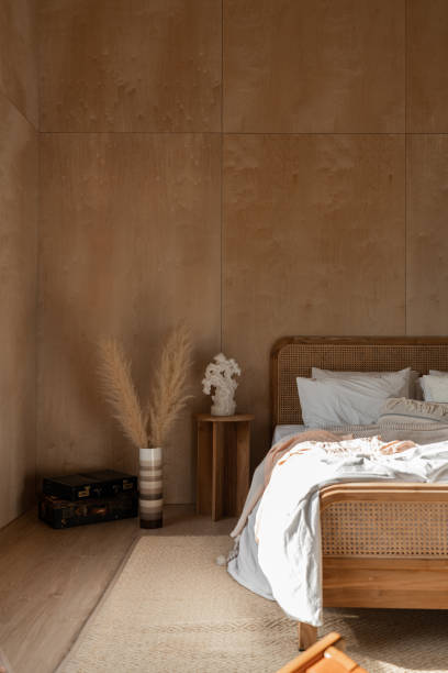 istock Stylish Bedroom corner with rattan headboard and bed with soft pillows setting with white pillows plywood wall on the background / cozy interior design / modern interior 1277932952