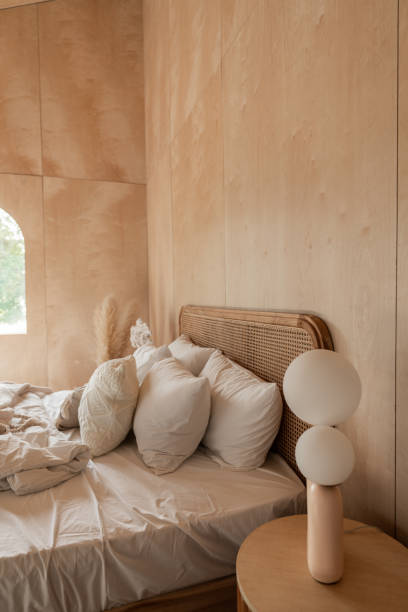 istock Stylish Bedroom corner with rattan headboard and bed with soft pillows setting with white pillows plywood wall on the background / cozy interior design / modern interior 1277932953
