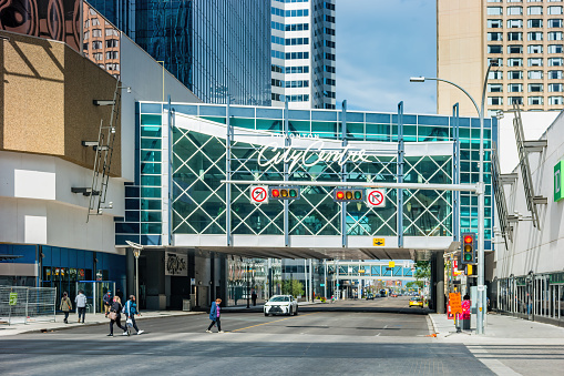 Pedestrians cross the street beside the Edmonton City Centre shopping mall in downtown Edmonton, Alberta, Canada on a sunny day.