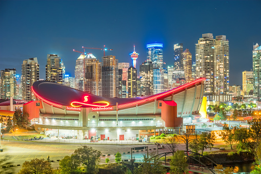 Skyline of Calgary Alberta Canada with the Scotiabank Saddledome arena in the foreground at night.