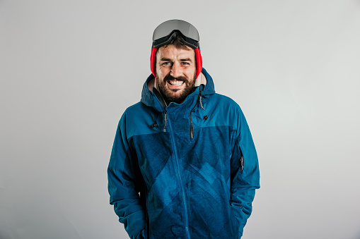 Portrait of a man in winter sports clothing in the studio with a grey background and copy space.