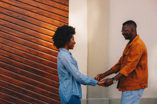 istock Young handsome african american hipster couple holding hands and being happy while standing on the street. 1277946565