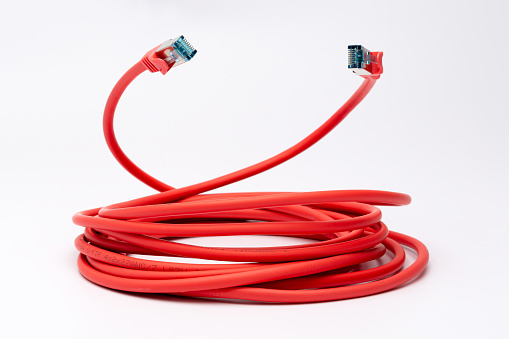Coiled red ethernet cable with twith two RJ45 plugs pointing upwards